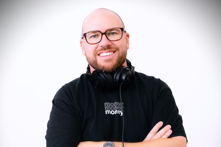 A smiling young man with headphones around his neck faces the camera.
