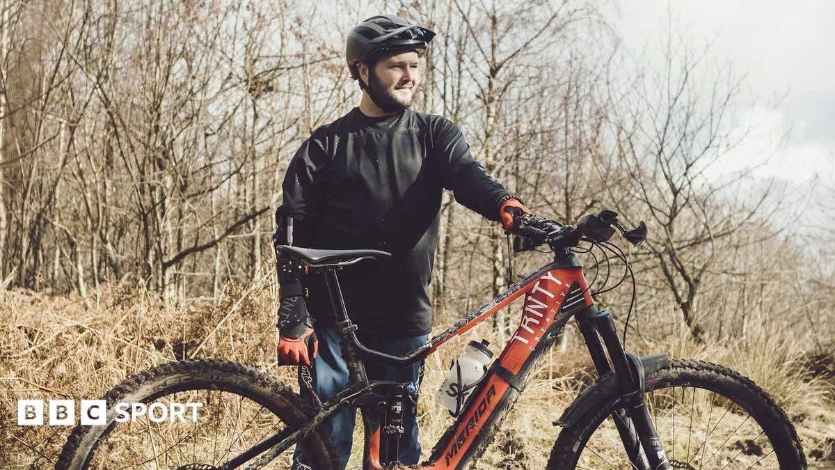 Tom Wheeler sits at a picnic table with his mountain bike behind him.