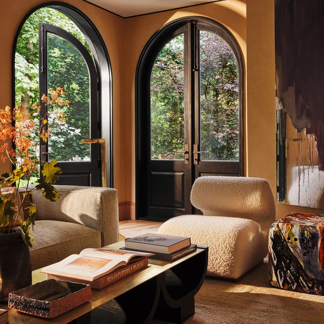 Elegant living room with arched glass doors, cozy seating, art, and a view of greenery outside. Elegant living room with arched glass doors, cozy seating, art, and a view of greenery outside.