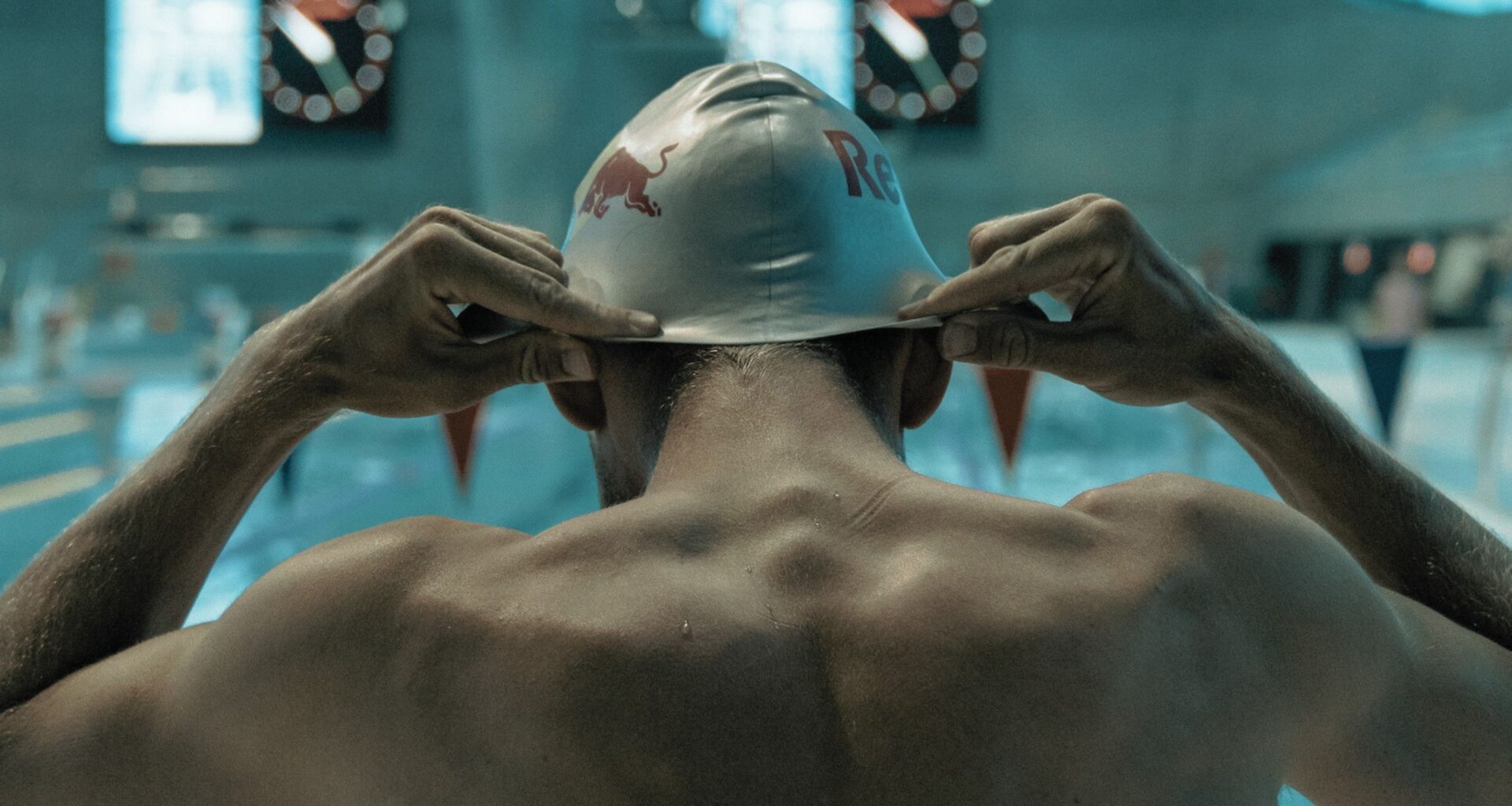 A swimmer putting on his swim cap.