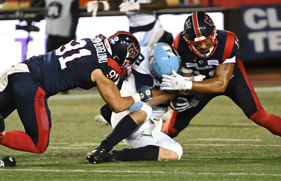 Alouettes defensive lineman Isaac Adeyemi-Berglund (91) and linebacker Geoffrey Cantin-Arku tackle Argonauts quarterback Chad Kelly in the 2024 East final, November 9, 2024 in Montreal. THE CANADIAN PRESS/Graham Hughes