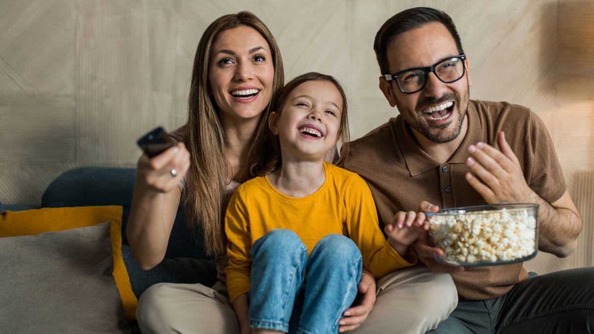 Family laughing together while watching television at home