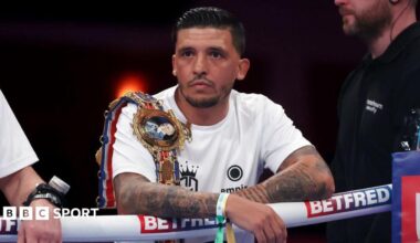 Lee Selby wears a white t-shirt with a Lonsdale belt over his shoulder, leaning on the ropes from the ring apron ahead of a Joe Cordina fight in Cardiff