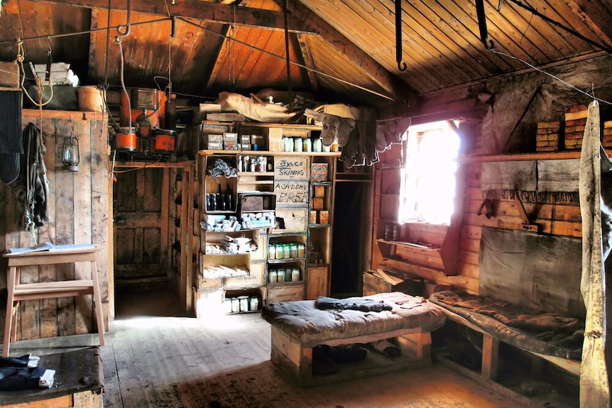 The wooden interior of Shackleton's hut, with shelves full of equipment and provisions.