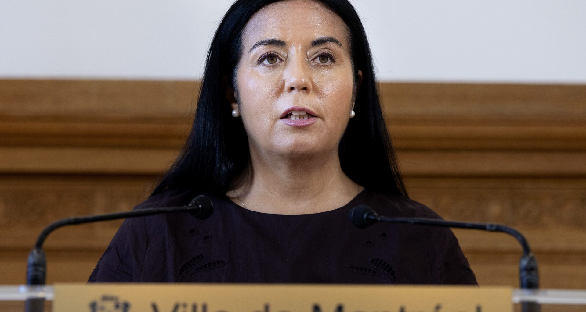 Woman speaks into mics at podium.