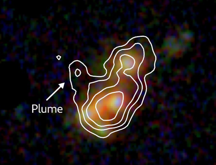 A patch of orange, green and purple light against a black background.