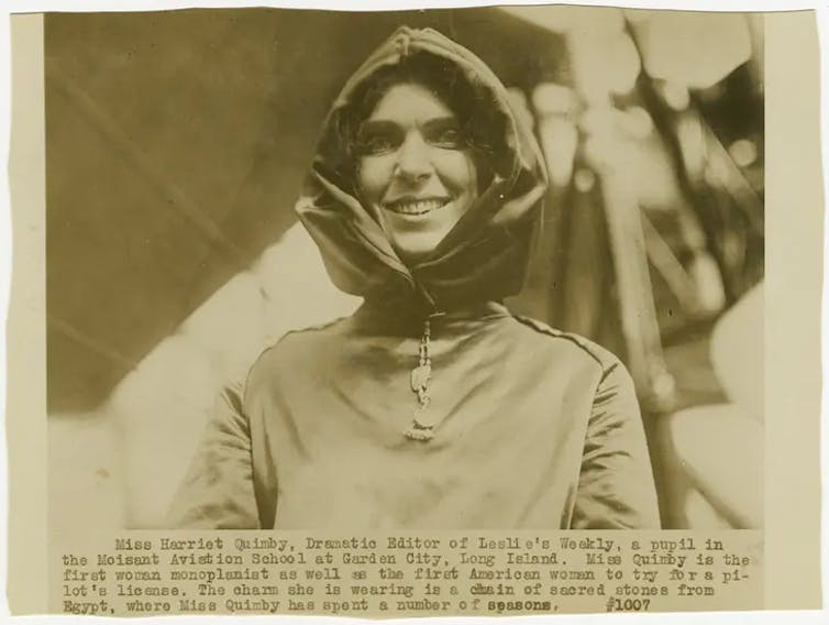 A black and white photo of a grinning woman wearing a flight suit