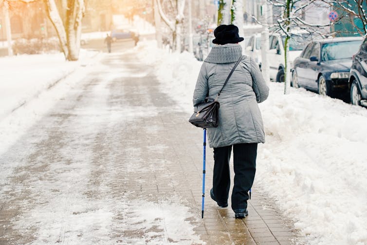 An elderly person walking on an icy path.