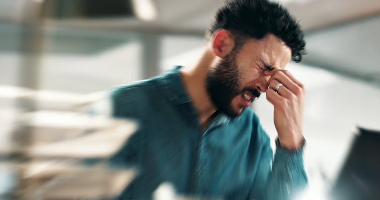 A man clenches his forehead stressed out.