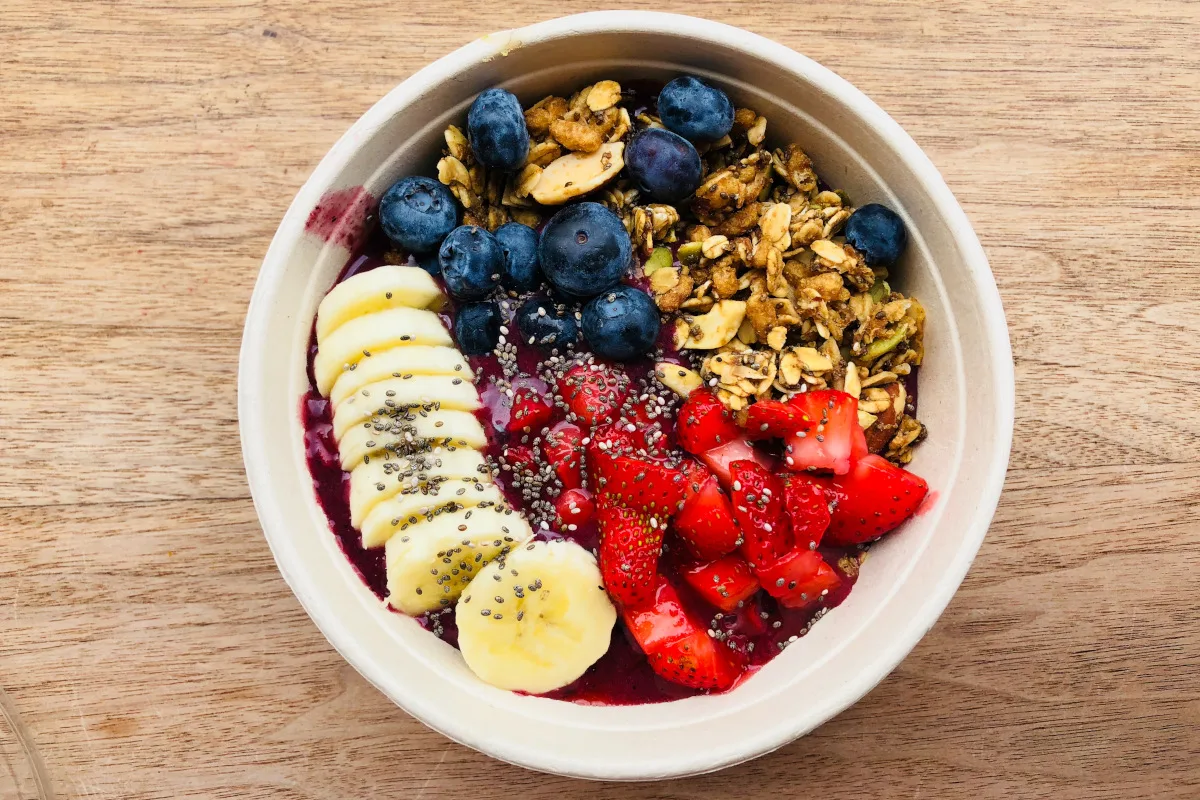 Acai bowl topped with bananas, blueberries, strawberries, granola, and chia seeds