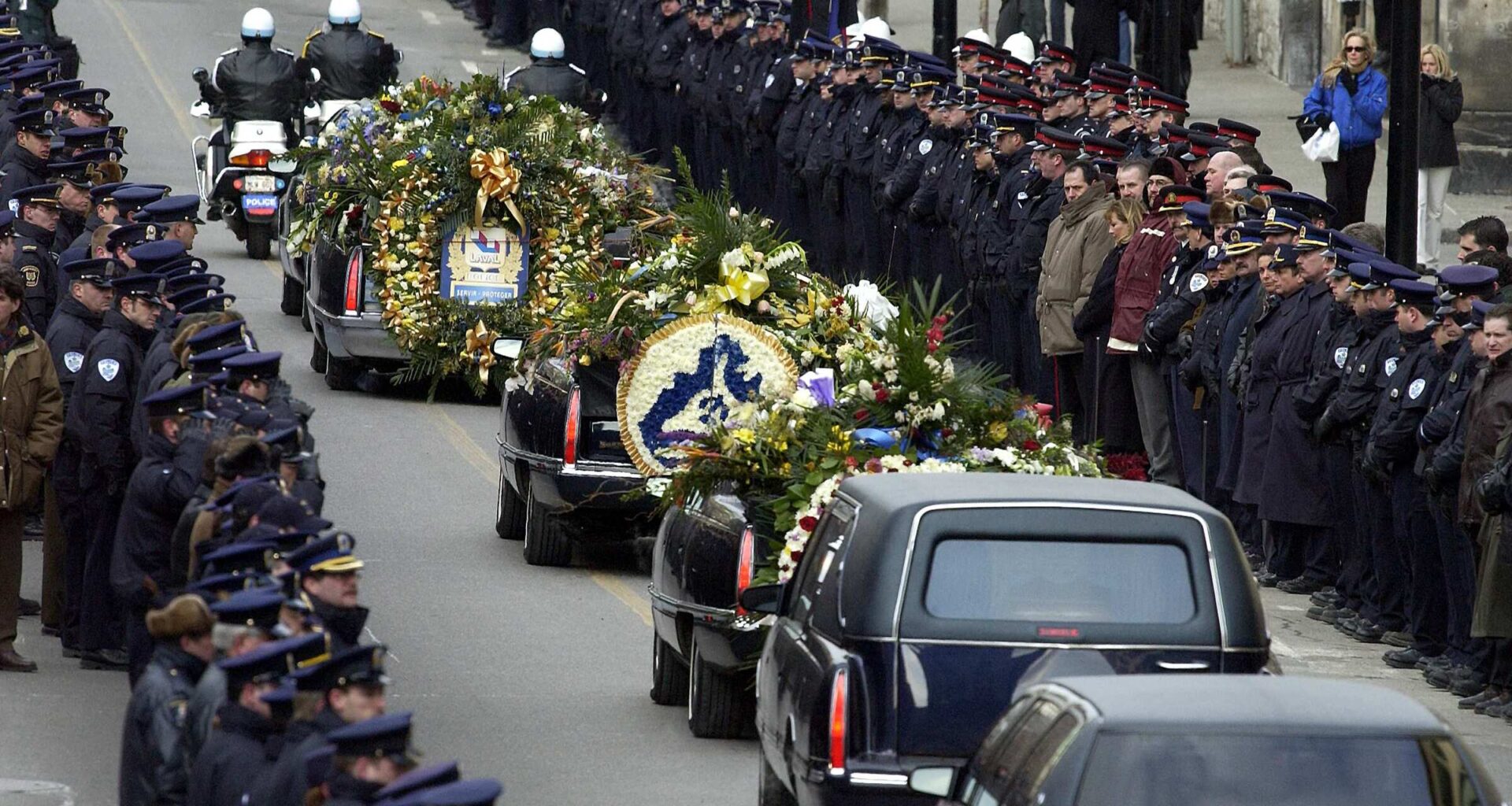 A funeral procession passes between two lines of police officers.