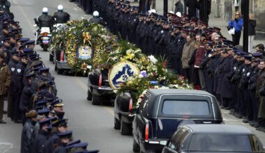 A funeral procession passes between two lines of police officers.