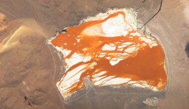Satellite photo showing bright orange water "bleeding" across the white bed of a slat lake