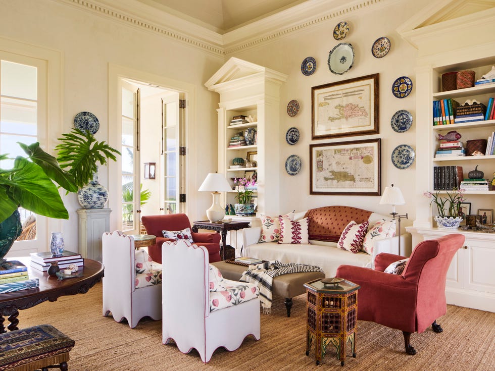 living room with cream colored walls, tall bookcases, wall art, and a grouping with a couch and four chairs