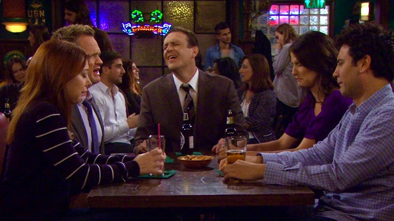 Lily, Barney, Robin, and Ted seated in bar looking disgusted while Marshall tells a story