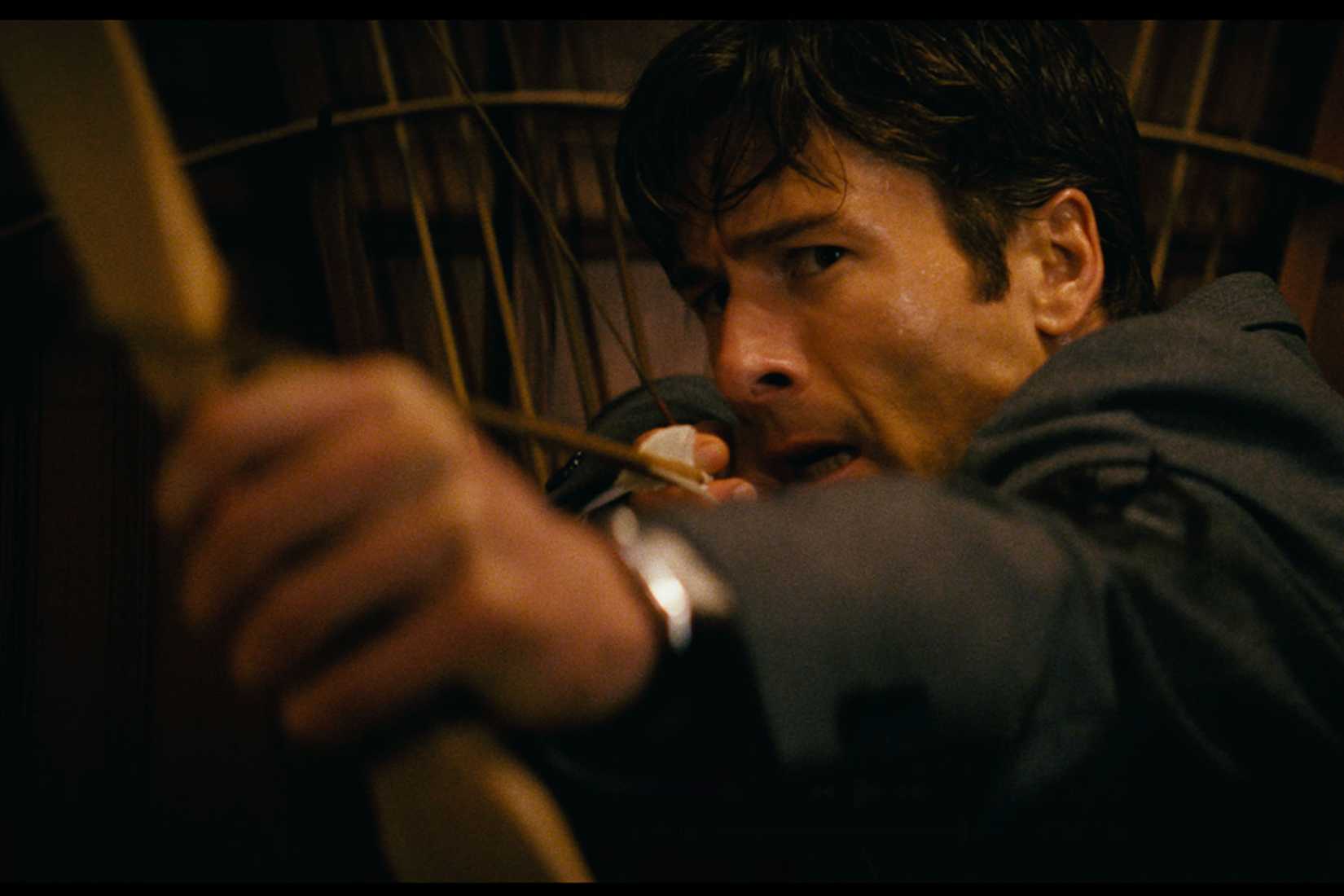 Glen Powell holding a bow in How To Make a Killing