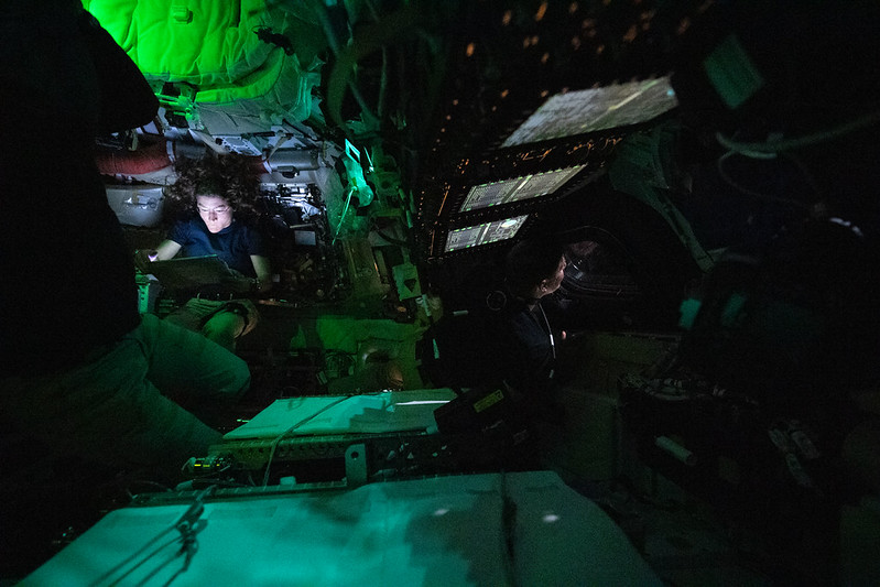 A view of the crew of Artemis II, working in the spacecraft with the lights dimmed.