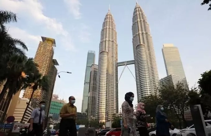 People walk outside the Petronas Towers in Kuala Lumpur, Malaysia. Photo by Reuters