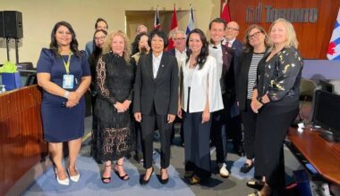 A group of people pose inside a City of Toronto office.