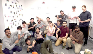A group of young people posing on the floor of an office.