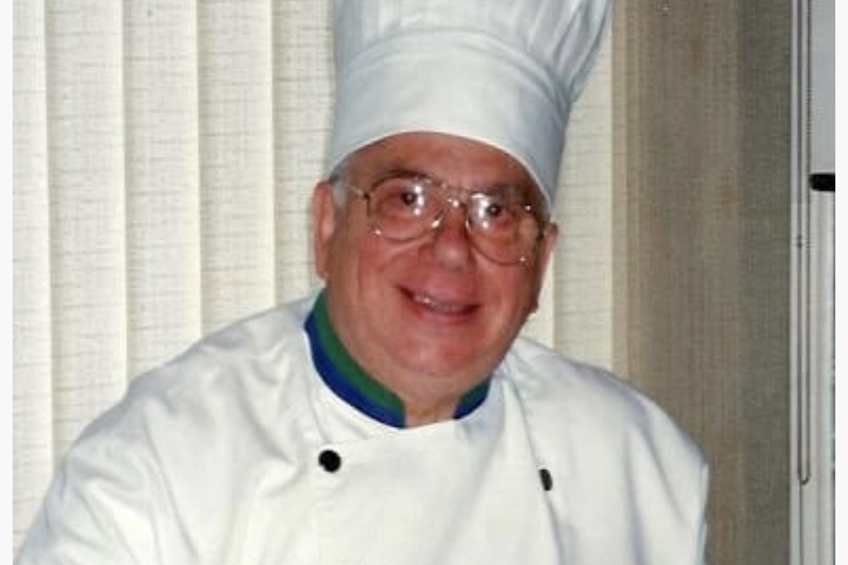 A male chef dressed in whites and hat.