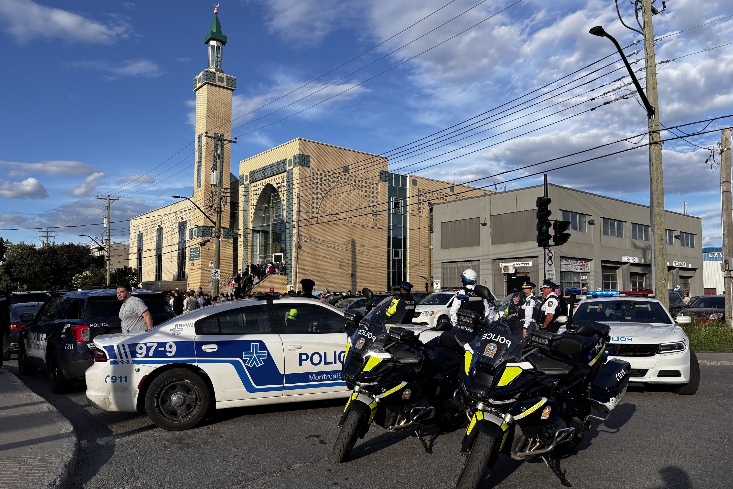 A mosque is seen from a distance, surrounded by Montreal police vehicles and officers who have gathered for a funeral.