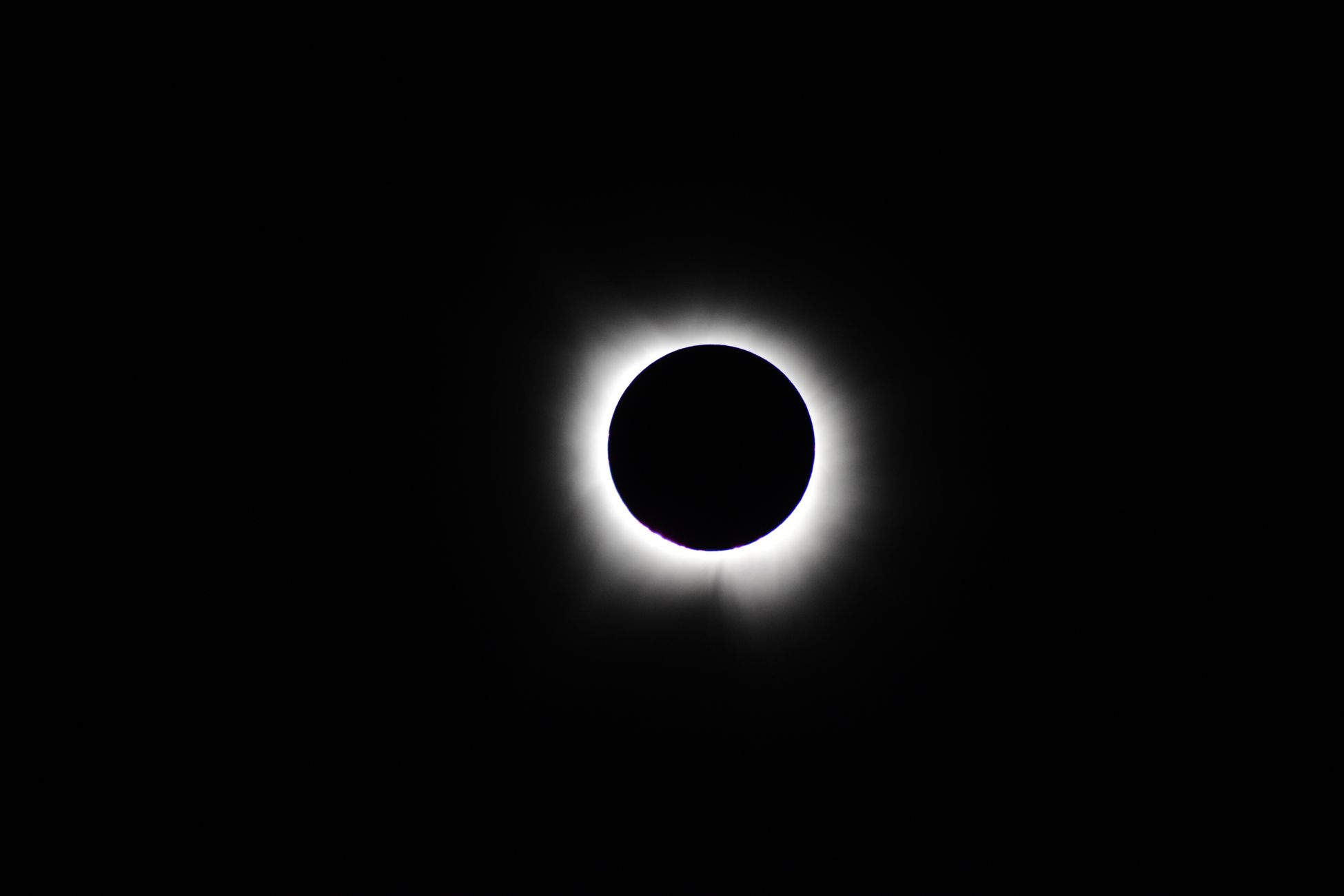 Dramatic total lunar eclipse featuring a glowing solar corona against a black sky.