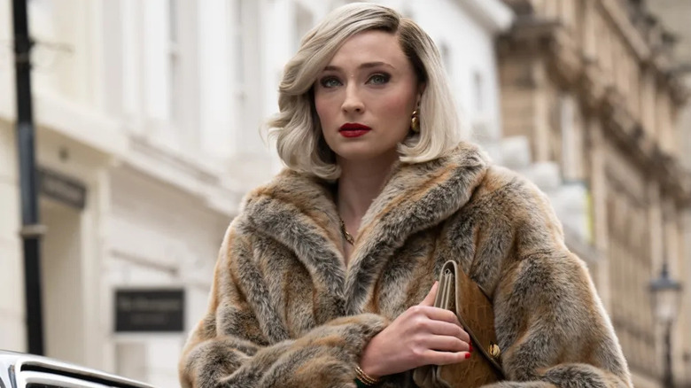 Joan Hannington (Sophie Turner) walks through London wearing a fur coat in Joan