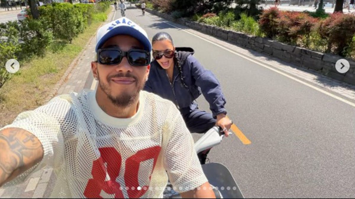 Kim Kardashian and Lewis Hamilton smiling as they rode bicycles next to each other.