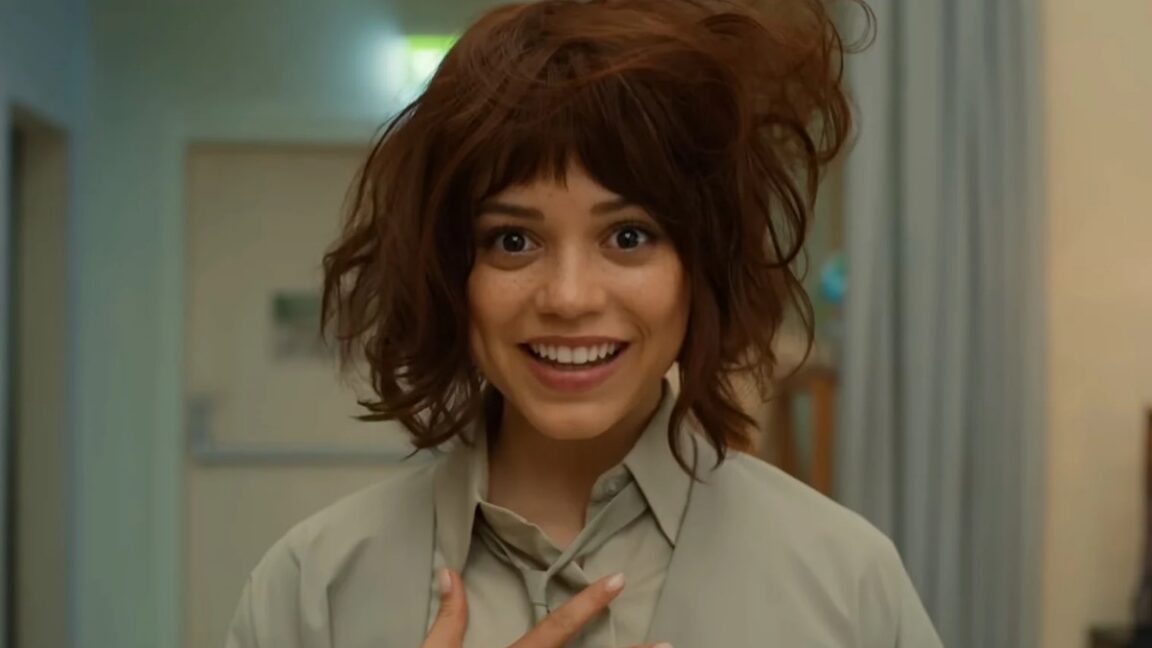 pretty brunette humanoid with tousled hair smiling into the camera, one hand on her chest as if to say "This is me"