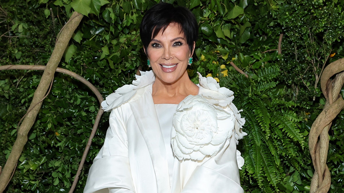 Kris Jenner standing in a white dress at a party venue