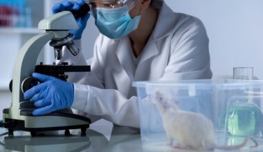 A scientist in a lab coat examines a sample under a microscope beside a white rat in a clear container.