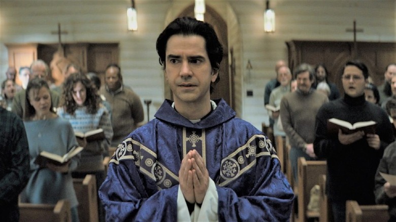 Father Paul Hill walking through a church, hands in prayer