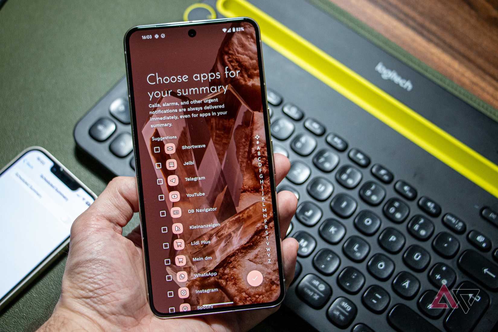 A Google Pixel 8 Pro held in hand, running Niagara Launcher's setup screen for notification summary, with a keyboard and an iPhone 13 visible in the background