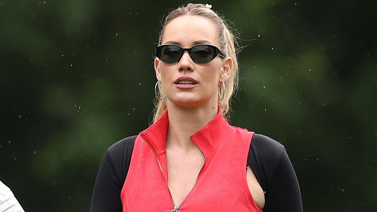 Paige Spiranac swinging a golf club on a golf course.
