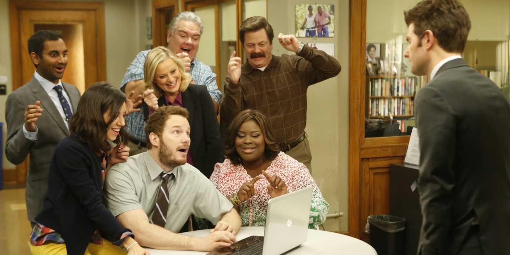 The cast of 'Parks and Recreation' gather around a computer and cheer
