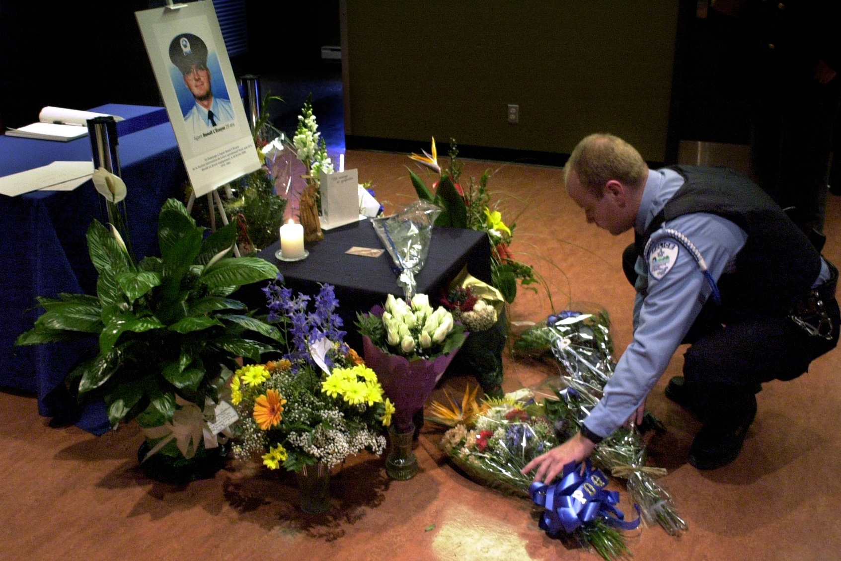 A police officer lays a wreath at a memorial for a fellow officer.