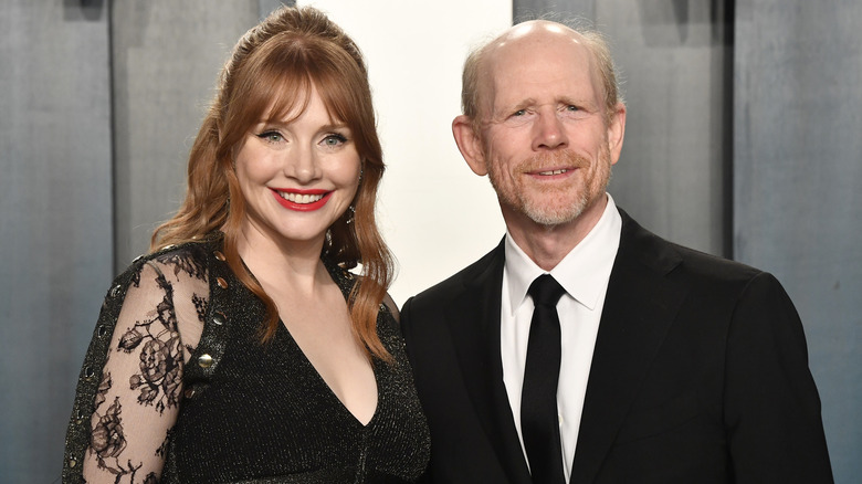 Bryce Dallas Howard and Ron Howard smiling while posing at an event in their finery