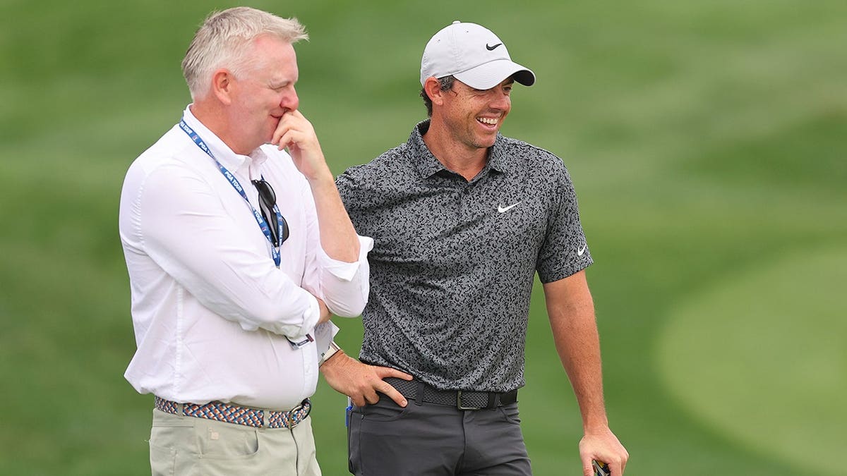 Rory McIlroy talking with Golfweek journalist Eamon Lynch at a golf course.