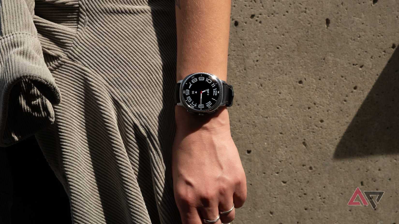 The Samsung Galaxy Watch 8 Classic on a wrist in front of a concrete wall