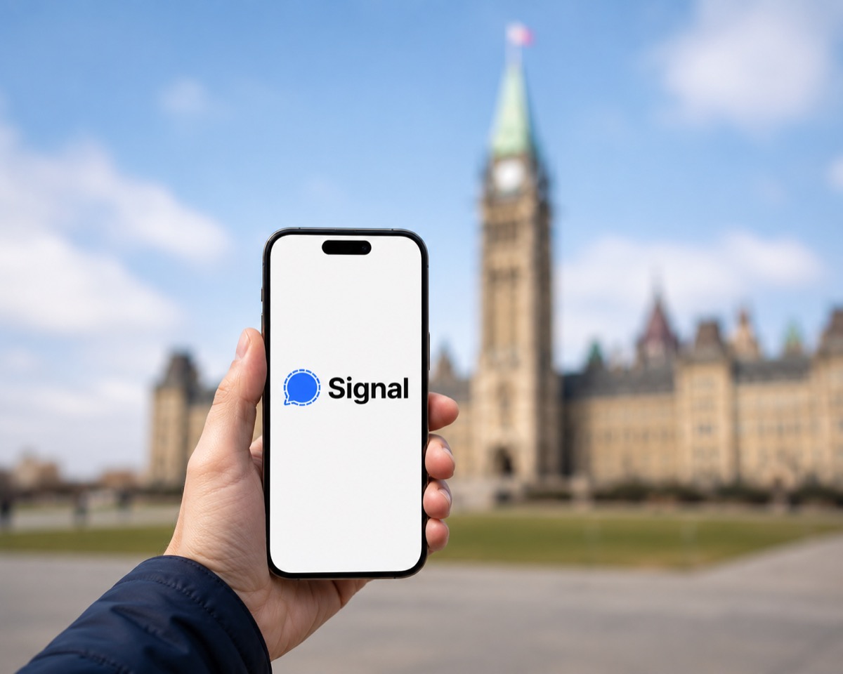 signal 2026 | iPhone in Canada Hand holding a smartphone displaying the Signal logo against a blurred historic building and blue sky outside.