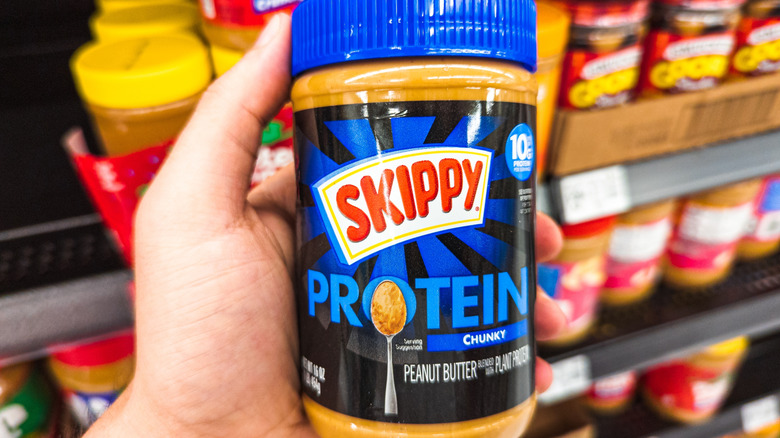 Hand holding jar of Skippy Protein in store