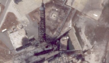 A charred black tower stands over debris after an exposion.