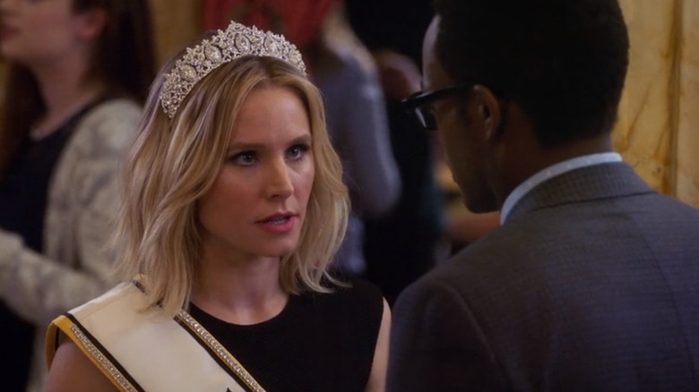 Eleanor wearing a tiara and sash talking to Chidi