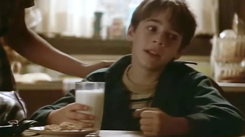 Georgie (Barret Oliver) holds a glass of milk while seated in a kitchen in The Twilight Zone (1985)