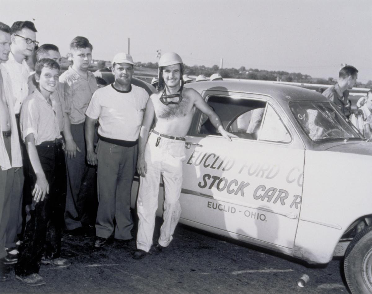 Group of men posing beside a vintage stock car with Euclid, Ohio lettering on the door.