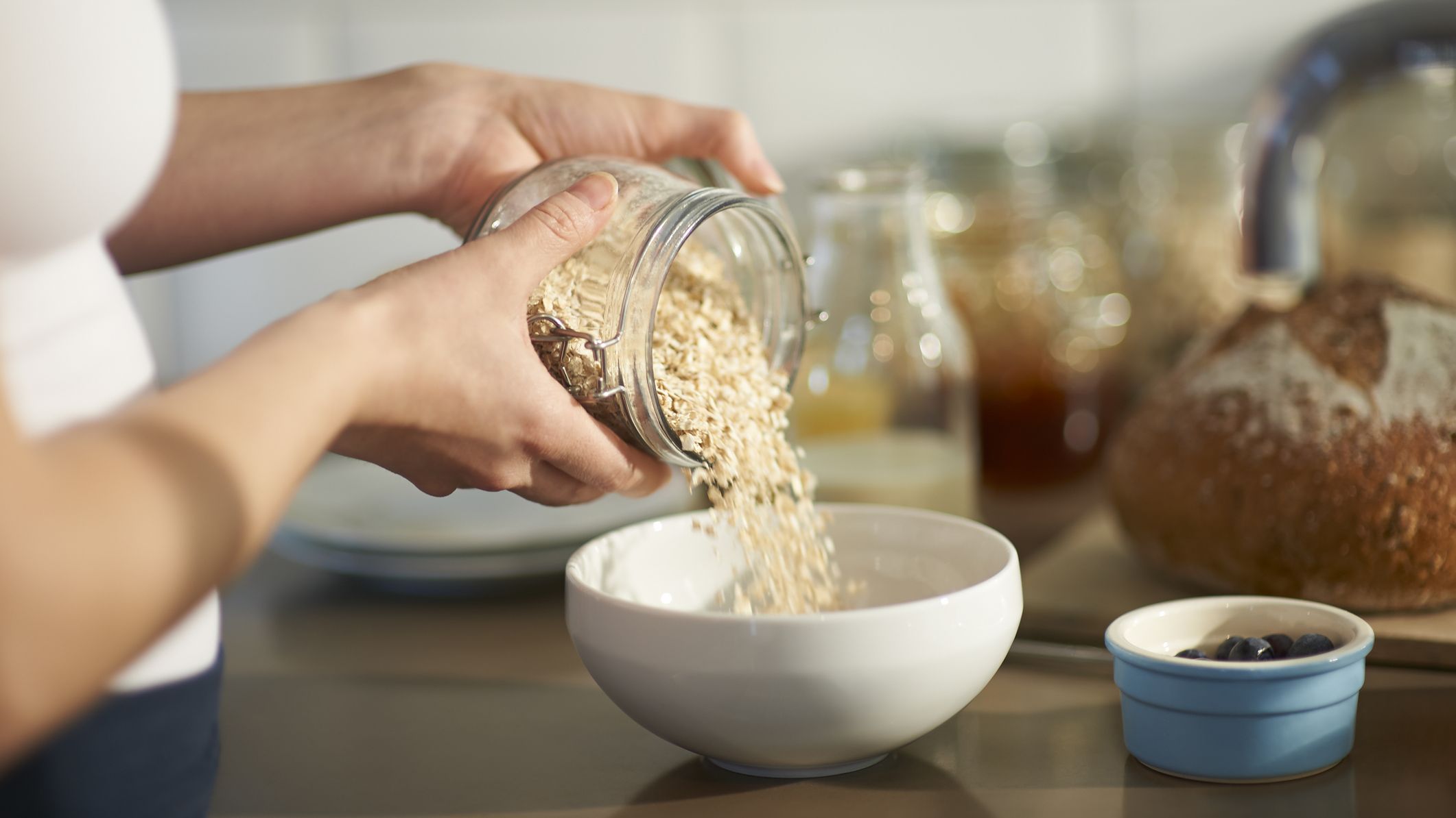 Woman pouring oats into a bowl on a kitchen counter