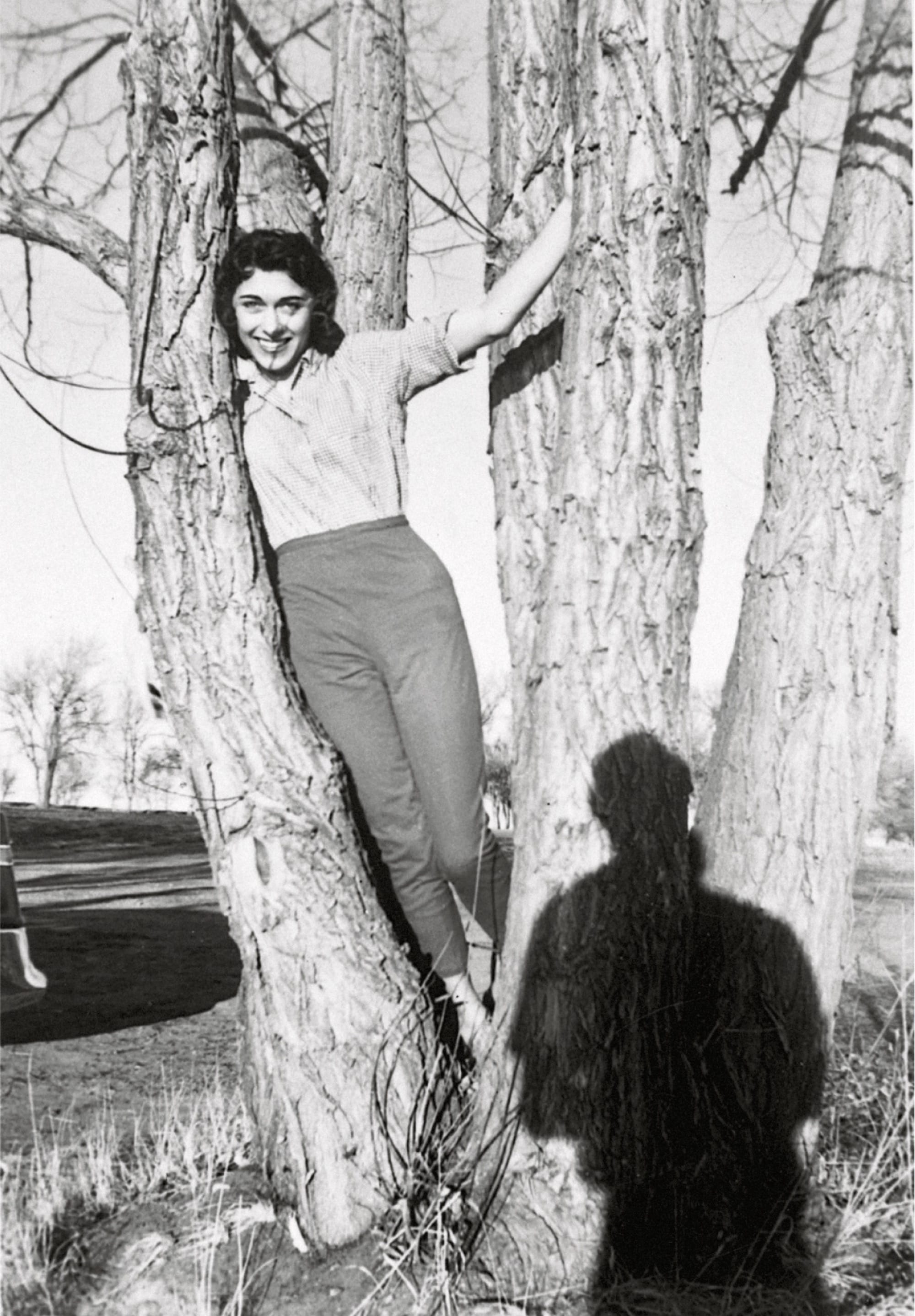 a black-and-white snapshot of a woman in a tree