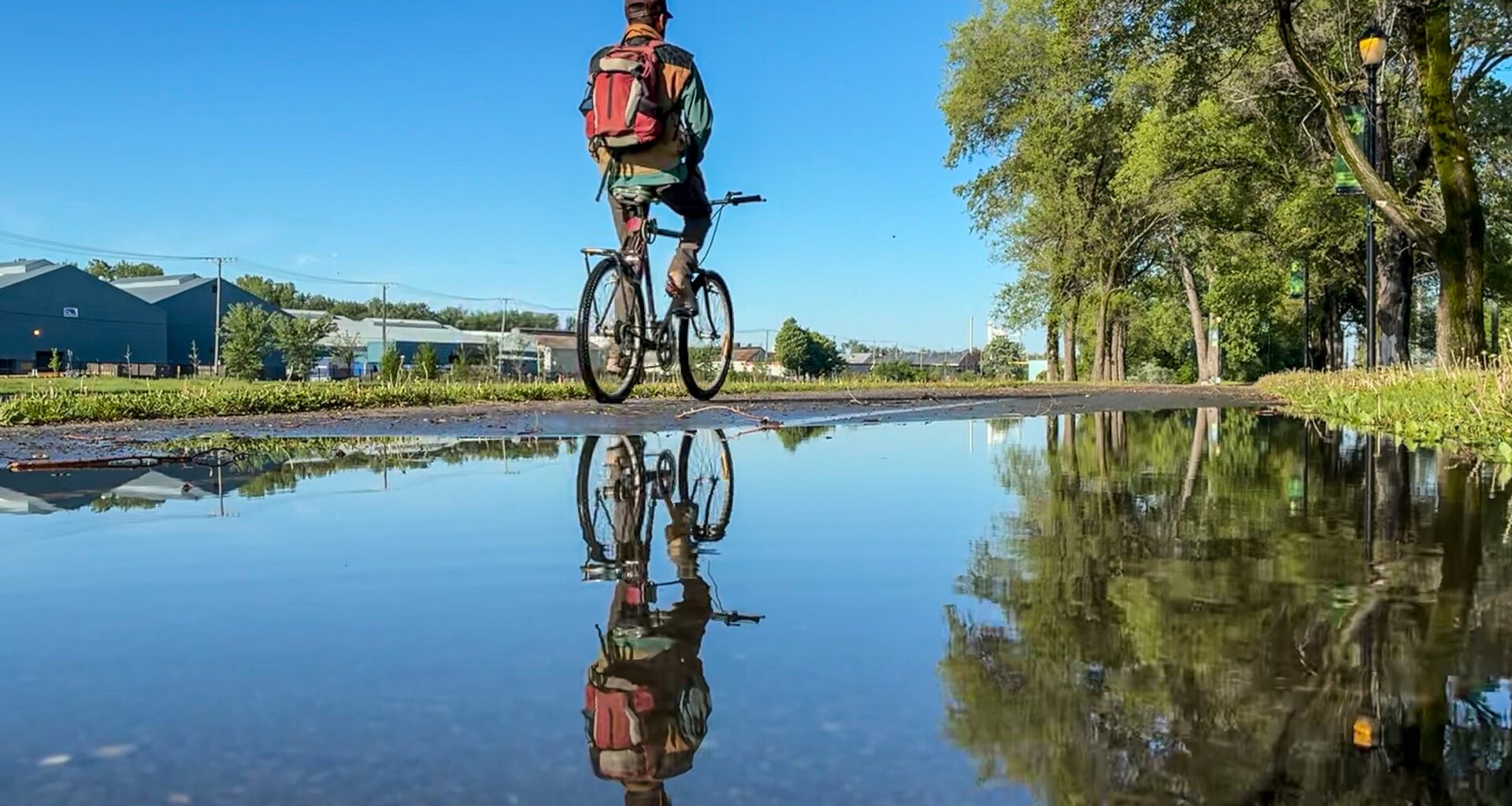 A person on a bike is reflected in a puddle.