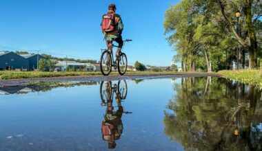 A person on a bike is reflected in a puddle.